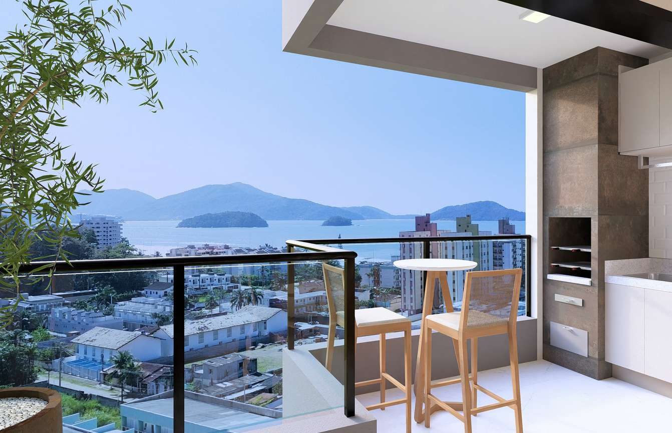 Varanda gourmet do apartamento de 43m² com churrasqueira, bancada, banquetas e vista para o mar e a serra.